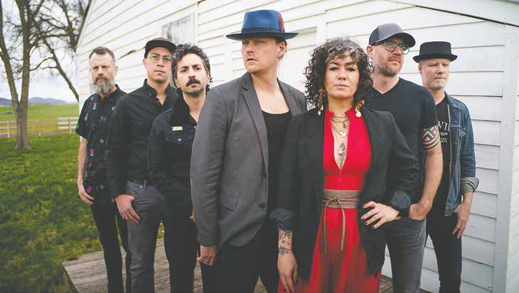 The seven members of Bywater Call gathered outside a white wooden building.
